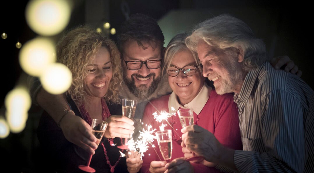 group two seniors two adults together having fun with sparlers new year celebrate happy family with lights midnight