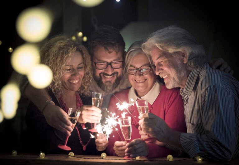 group of two seniors and two adults together having fun with sparlers the new year to celebrate - happy family with lights at midnight