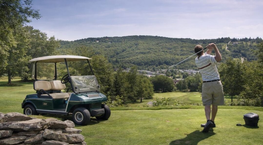 Golf resort in Catskills New York with golfer swinging on scenic course and golf cart at Villa Roma resort
