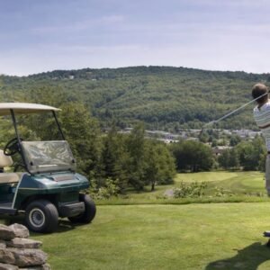 Golf resort in Catskills New York with golfer swinging on scenic course and golf cart at Villa Roma resort