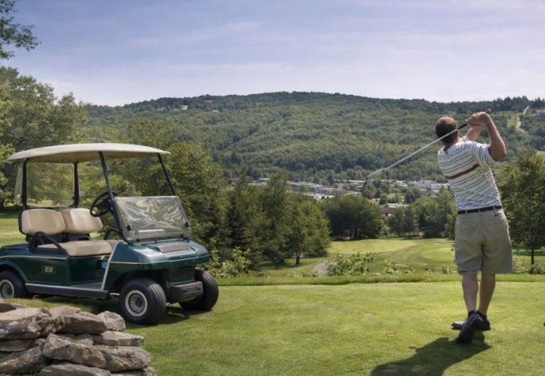 Golf resort in Catskills New York with golfer swinging on scenic course and golf cart at Villa Roma resort